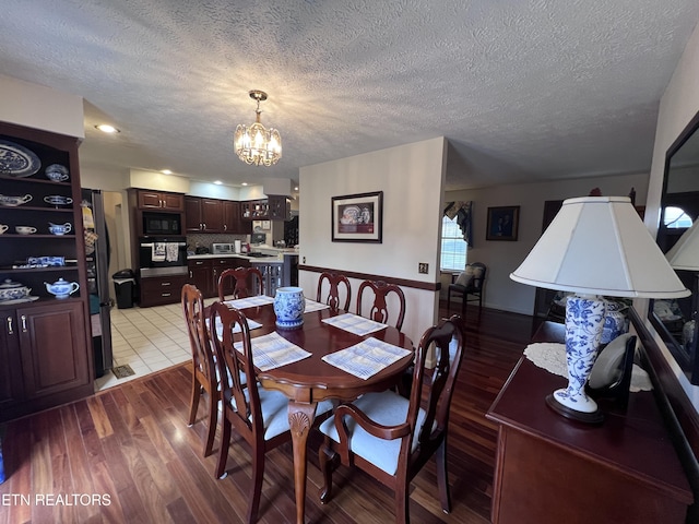 dining space featuring a notable chandelier, a textured ceiling, and wood finished floors