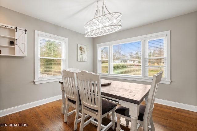 dining area featuring a barn door, wood finished floors, and baseboards