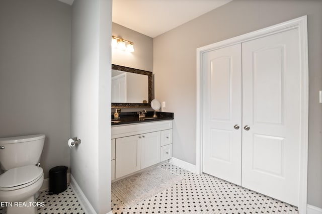 bathroom featuring baseboards, vanity, and toilet