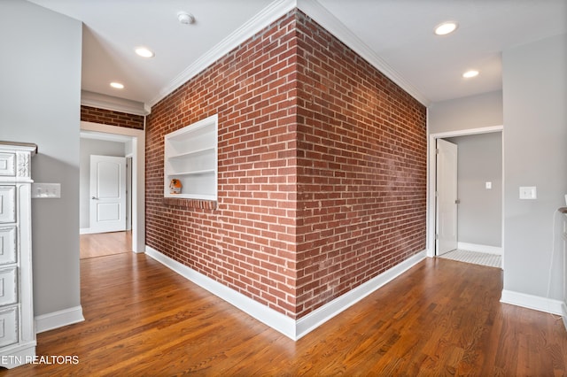 hall with built in features, brick wall, and wood finished floors