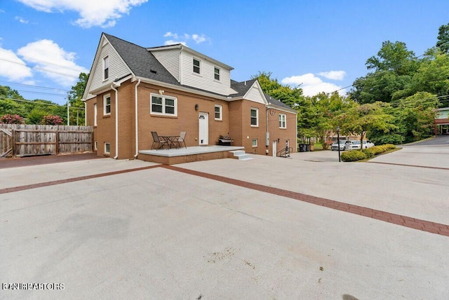 rear view of house featuring brick siding and fence