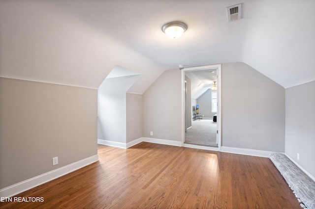 bonus room with baseboards, visible vents, vaulted ceiling, and wood finished floors