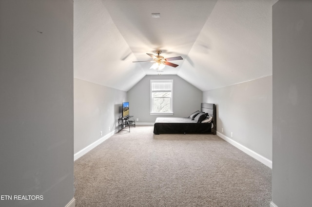 unfurnished bedroom featuring lofted ceiling, baseboards, and carpet flooring