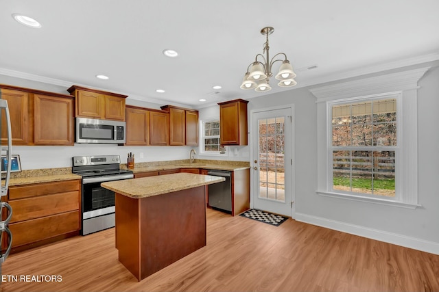 kitchen with light wood-style flooring, a kitchen island, a sink, ornamental molding, and appliances with stainless steel finishes