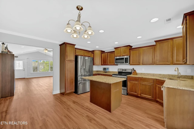 kitchen featuring a sink, light wood-style floors, stainless steel appliances, and crown molding