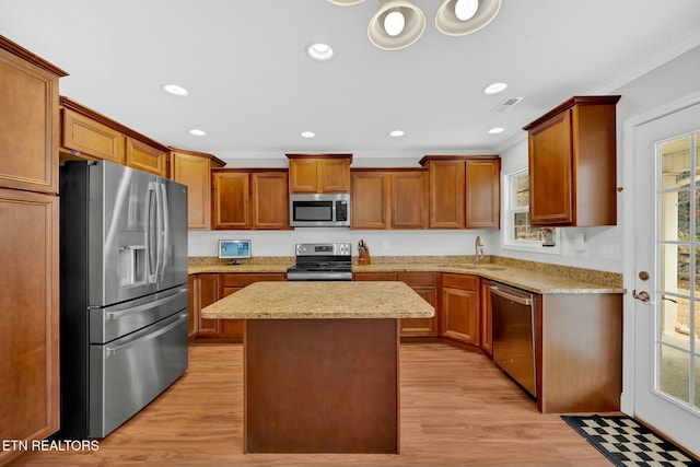 kitchen featuring visible vents, stainless steel appliances, crown molding, light wood-type flooring, and a sink