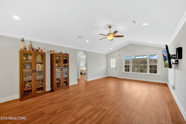 unfurnished living room featuring arched walkways, crown molding, visible vents, vaulted ceiling, and wood finished floors