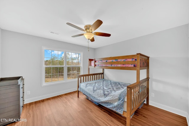 bedroom featuring visible vents, wood finished floors, a ceiling fan, and baseboards