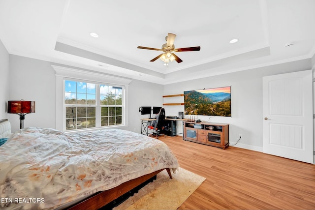 bedroom featuring recessed lighting, baseboards, light wood-type flooring, a raised ceiling, and crown molding