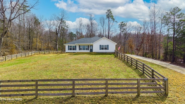 view of front of property with a wooded view, a front yard, and fence