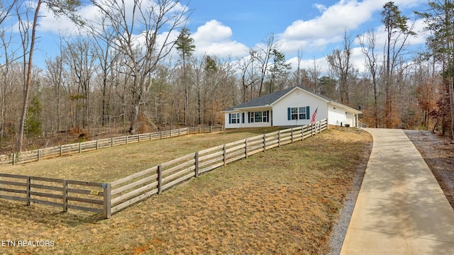 view of front of property with a garage, fence, a view of trees, and a front yard