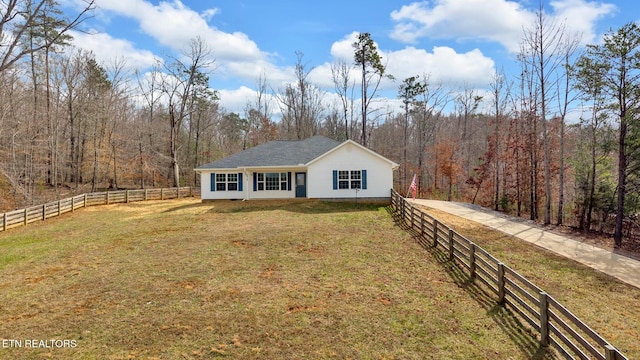 view of front facade featuring fence private yard, a front lawn, and a view of trees