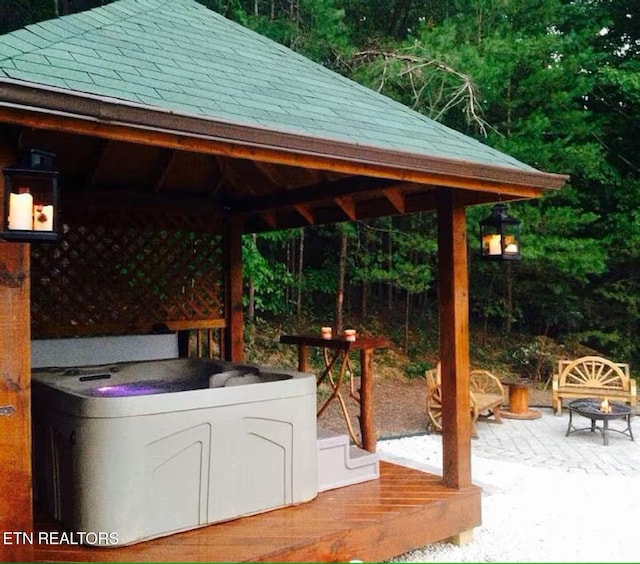 view of patio with a hot tub, an outdoor fire pit, separate washer and dryer, and a gazebo