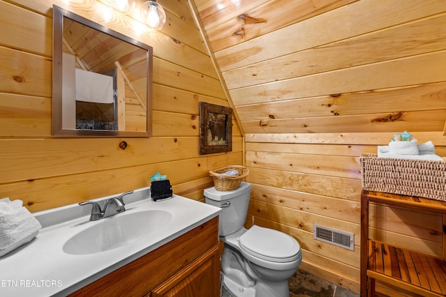 half bathroom with toilet, wood walls, visible vents, and vanity