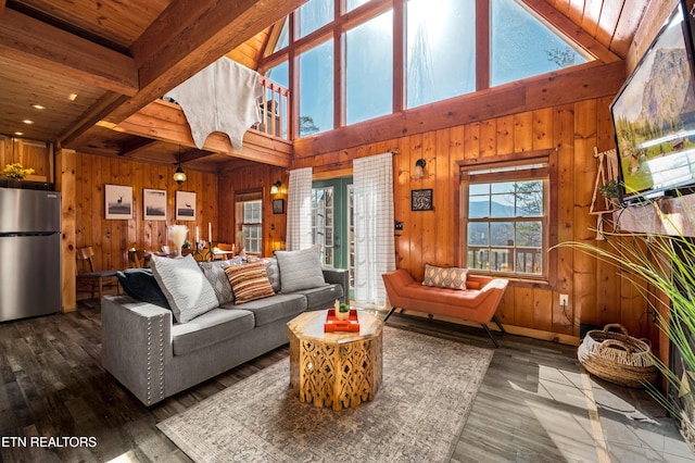 living area with beamed ceiling, wooden walls, and wood finished floors