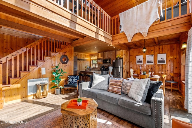 living room with wood walls, stairway, wood-type flooring, and visible vents