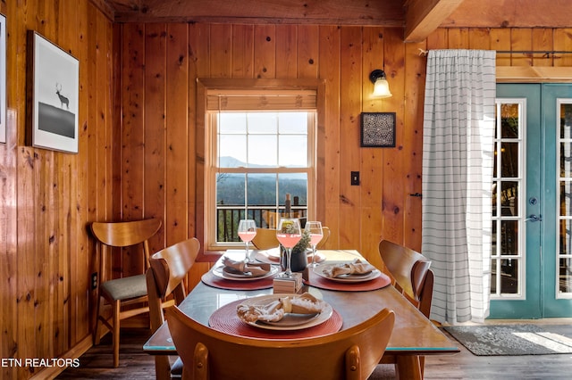 dining room featuring french doors, wood walls, and wood finished floors