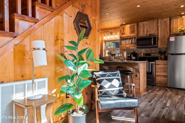 kitchen with wooden ceiling, appliances with stainless steel finishes, dark wood finished floors, and wood walls