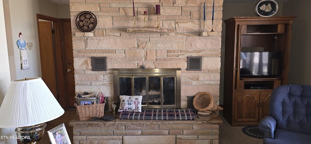 living area featuring visible vents and a stone fireplace