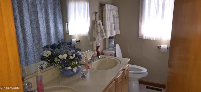 bathroom featuring visible vents, vanity, toilet, and baseboards