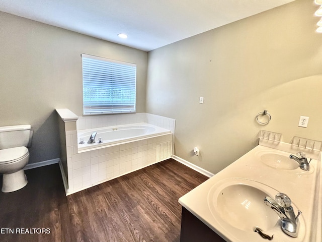 full bathroom with a bath, wood finished floors, toilet, and a sink