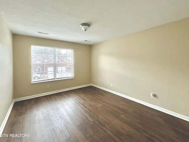 unfurnished room featuring visible vents, baseboards, and dark wood-style flooring