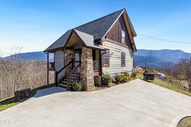 view of front of house featuring stone siding, a mountain view, and roof with shingles