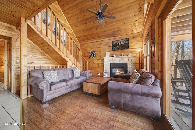 living room featuring wood-type flooring, wooden walls, wooden ceiling, a fireplace, and vaulted ceiling