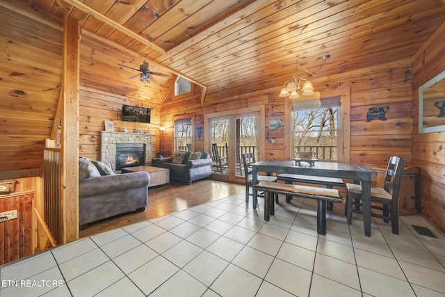 dining area featuring visible vents, wood walls, a fireplace, light tile patterned floors, and wood ceiling