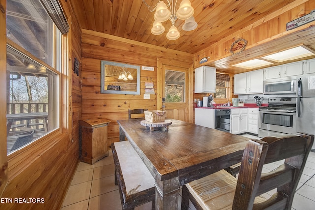 dining area featuring light tile patterned floors, a notable chandelier, wood ceiling, and wood walls