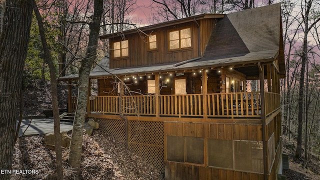 back of property at dusk with roof with shingles