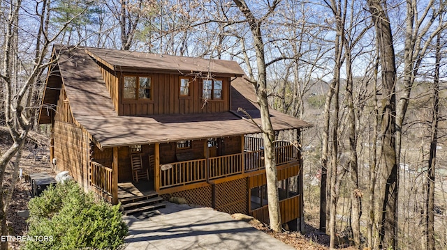 rustic home with board and batten siding, a shingled roof, and covered porch