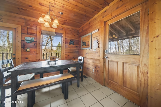 dining room featuring light tile patterned flooring, wooden walls, wooden ceiling, and an inviting chandelier