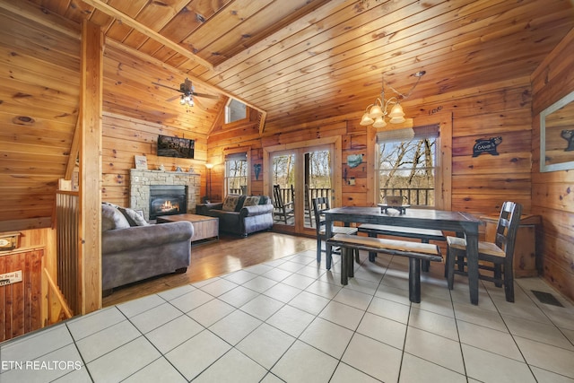 dining area featuring wooden ceiling, vaulted ceiling, wooden walls, and light tile patterned floors