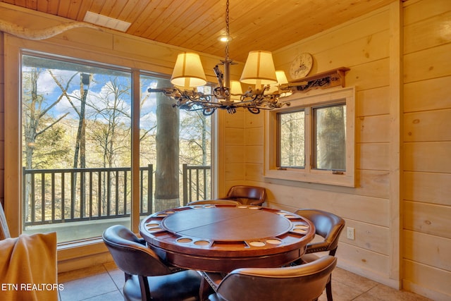 dining space featuring light tile patterned floors, wood ceiling, a notable chandelier, and wood walls