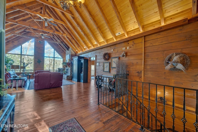 interior space featuring vaulted ceiling with beams, wood-type flooring, visible vents, wood ceiling, and wooden walls