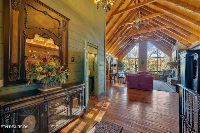 interior space with high vaulted ceiling, beamed ceiling, wood-type flooring, and wooden walls