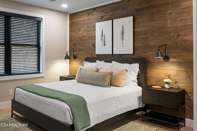 bedroom featuring recessed lighting, wood finished floors, baseboards, and wood walls