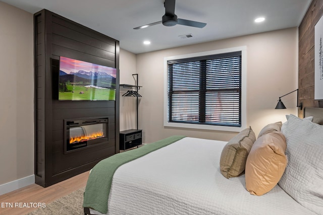 bedroom featuring baseboards, visible vents, recessed lighting, light wood-style floors, and a large fireplace