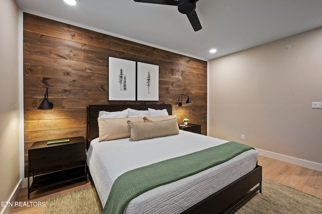 bedroom featuring wooden walls, baseboards, recessed lighting, wood finished floors, and a ceiling fan