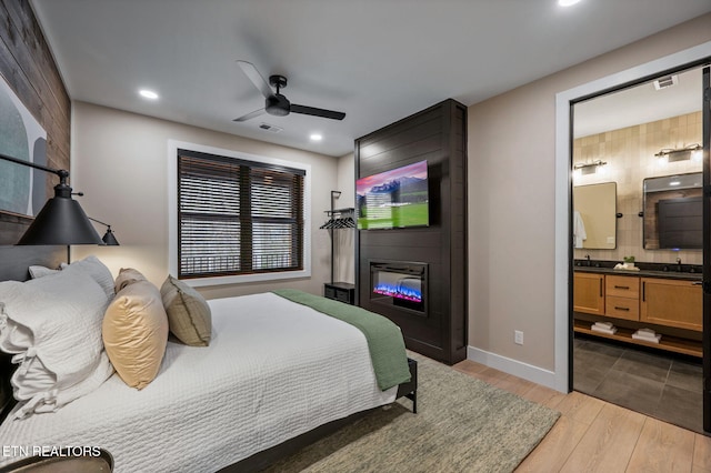 bedroom featuring visible vents, wood finished floors, connected bathroom, a fireplace, and baseboards