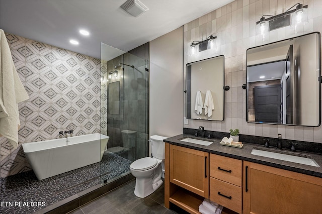 full bathroom with tile patterned flooring, tile walls, visible vents, and a sink