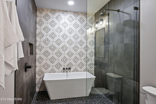 full bath with a freestanding tub, toilet, tile walls, and a tile shower