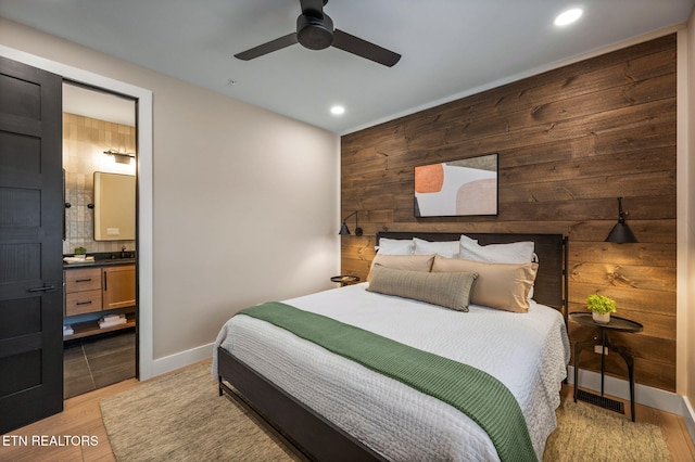 bedroom featuring recessed lighting, light wood-style flooring, baseboards, and wood walls