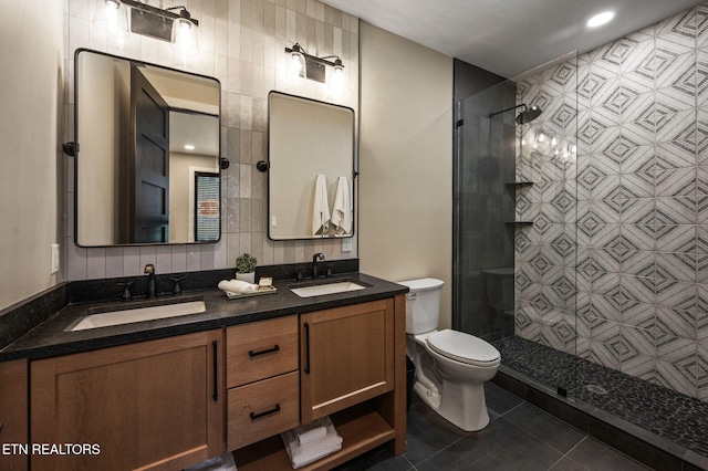 bathroom with tile patterned flooring, toilet, tiled shower, and a sink