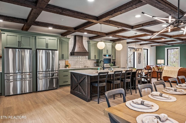 kitchen featuring premium range hood, light wood-type flooring, stainless steel appliances, light countertops, and green cabinetry