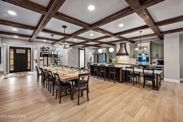 dining space featuring light wood finished floors, baseboards, stairway, beam ceiling, and coffered ceiling