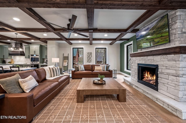 living area with beamed ceiling, coffered ceiling, recessed lighting, a stone fireplace, and baseboards