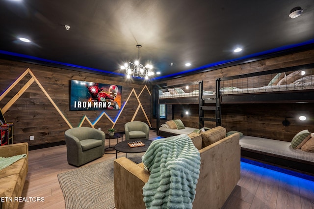 cinema featuring a chandelier, wood walls, and hardwood / wood-style flooring