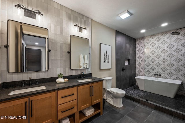 full bath with a sink, toilet, tile walls, and tile patterned floors